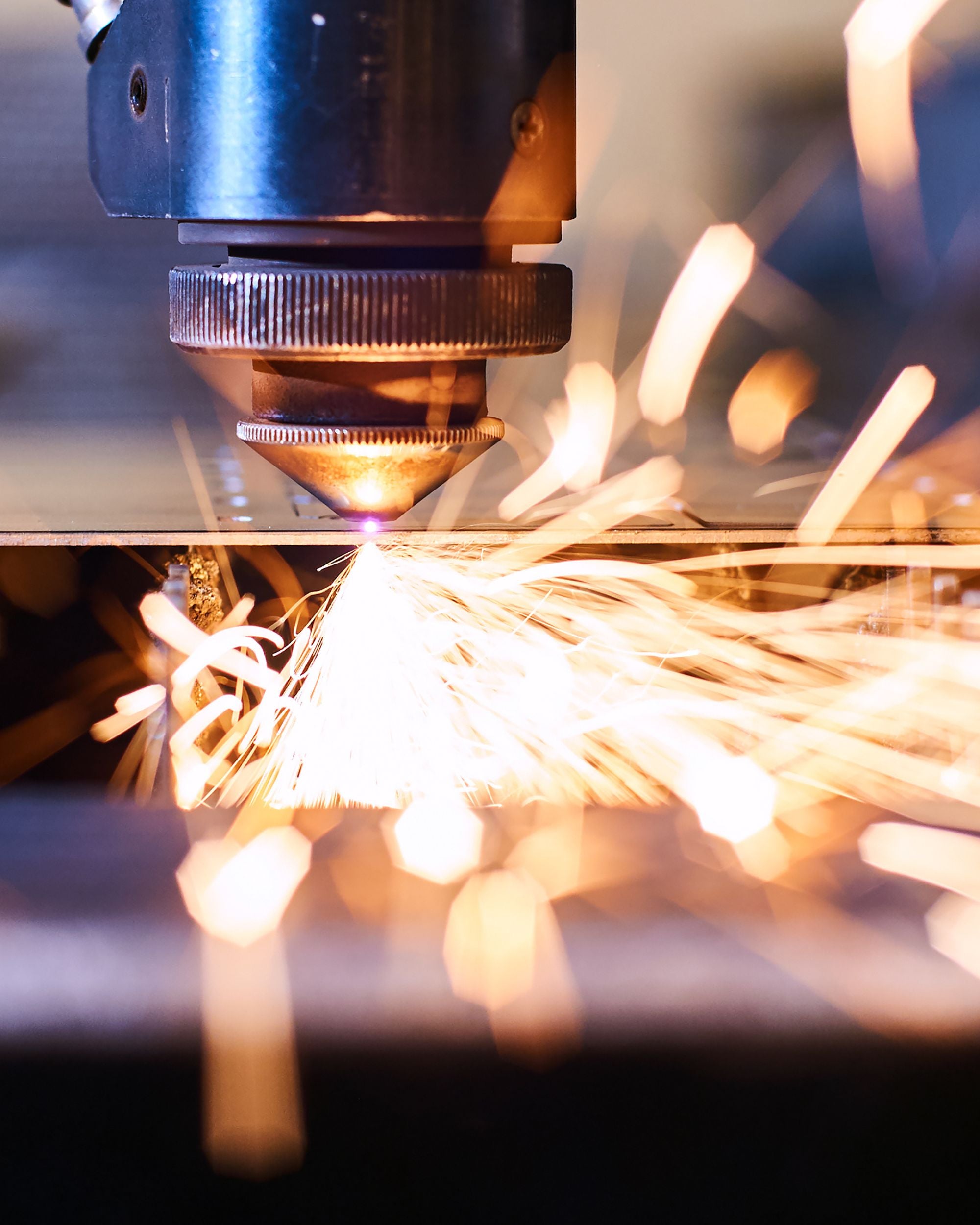 Laserstrahl beim Auslasern eines MOCAVI Motivs aus Metall für die Feuertonne