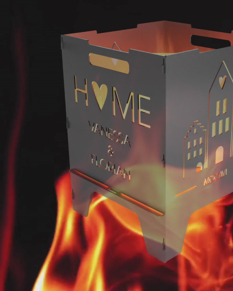 Video laden: Video ohne Ton mit rot lodernder Flamme im Hintergrund, im Vordergrund eine personalisierte Feuertonne mit Skandi Häusern und HOME Motiv.